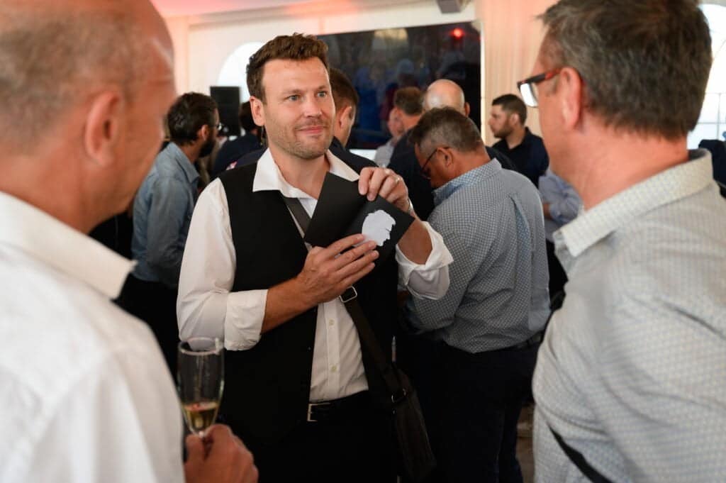 Morlon Silhouettiste en train de montrer le portrait qu'il vient de découper aux ciseaux à un invité pour un évènement d'entreprise