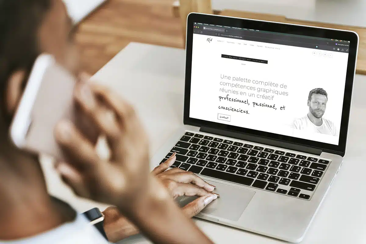 Graphiste illustrateur en communication téléphonique devant son ordinateur affichant le site internet de Morlon Création