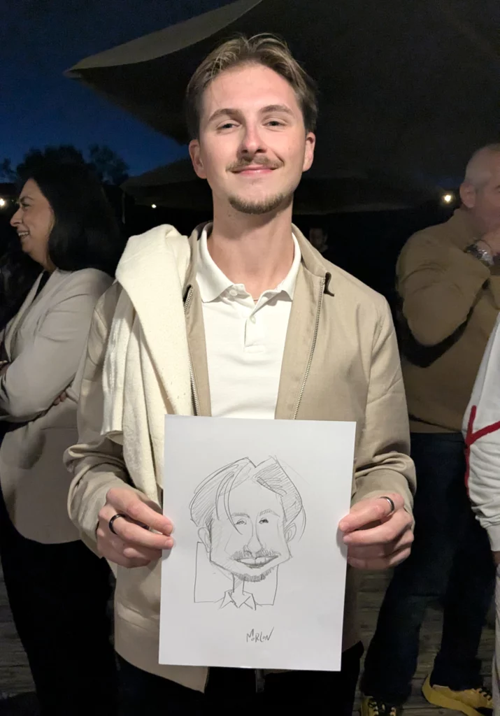 Jeune homme tenant sa caricature dessinée en soirée