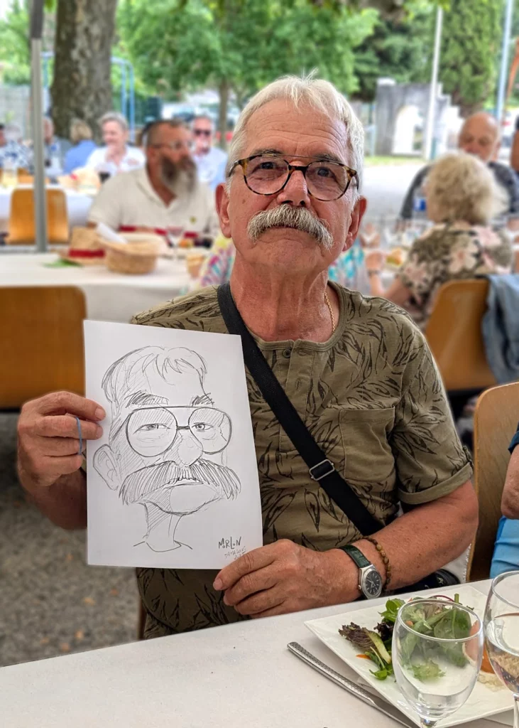 Homme présentant sa caricature réalisée en soirée